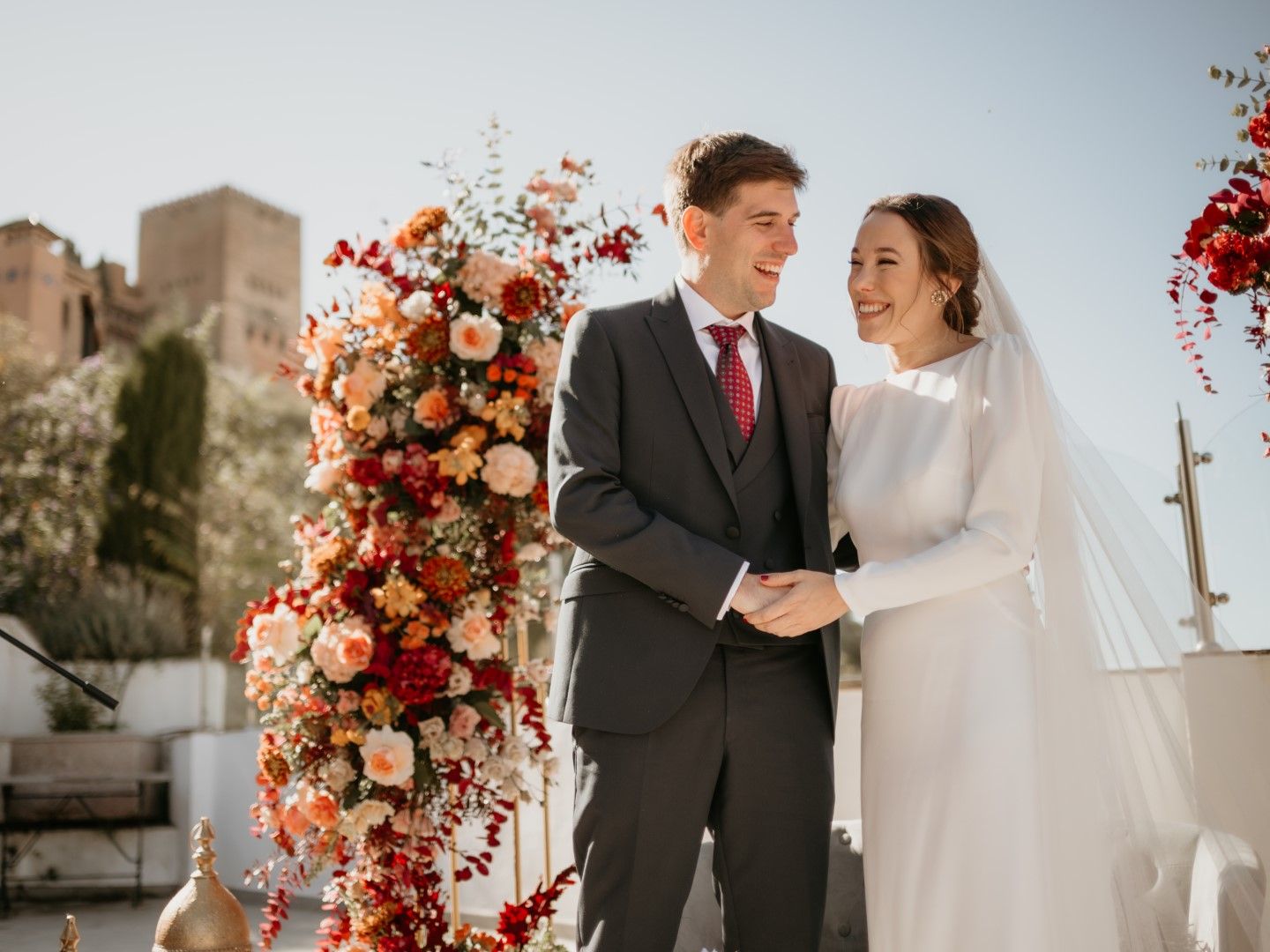 Novios en la terraza junto al arco floral con la Alhambra al fondo
