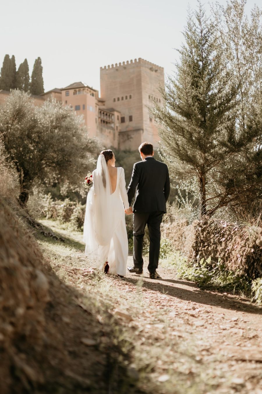 Novios paseando entre olivos bajo la Alhambra