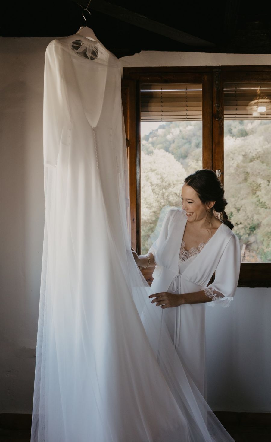 Novia preparándose junto a su vestido colgado