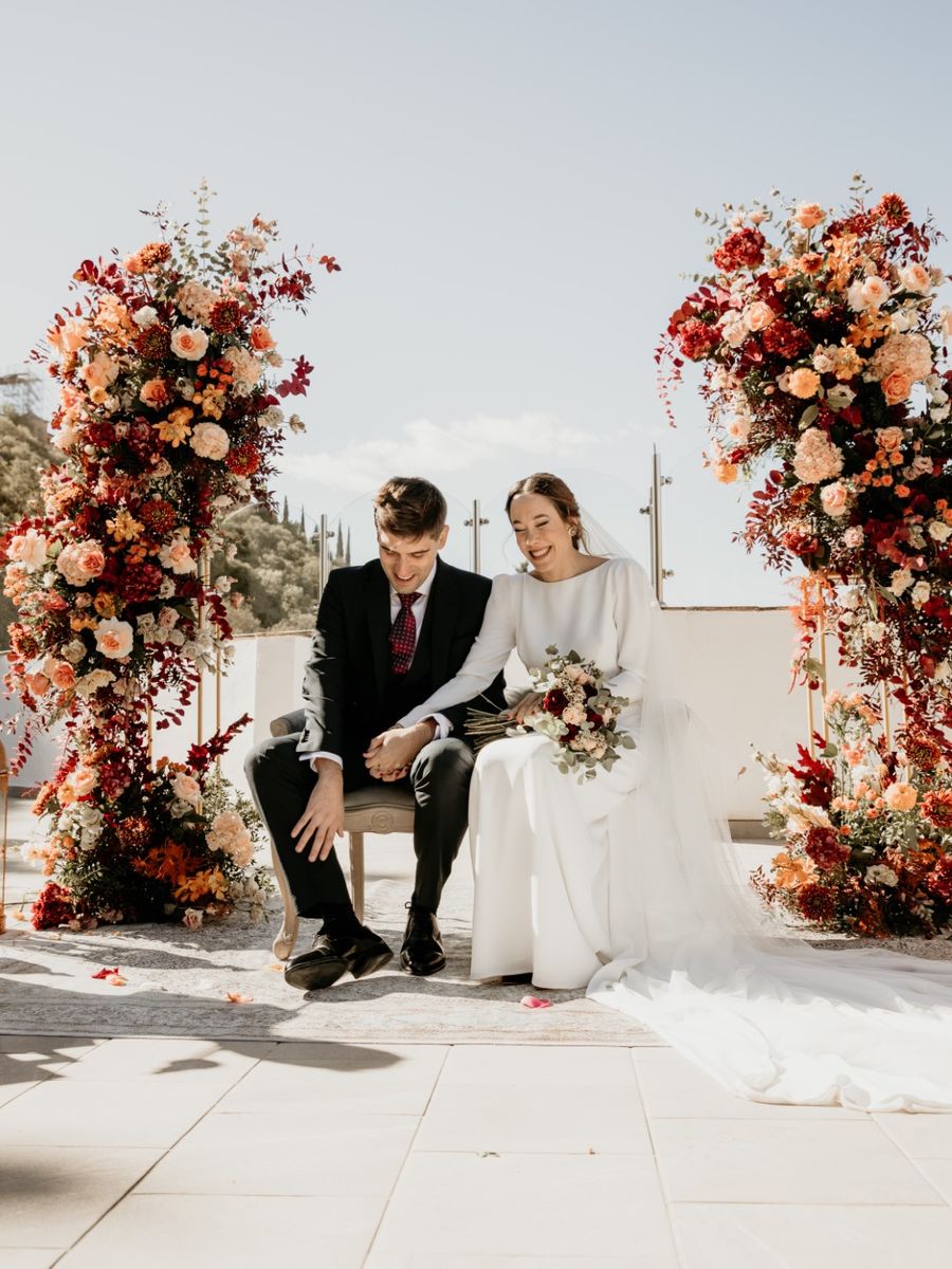 Novios sentados ante el altar de flores en la ceremonia