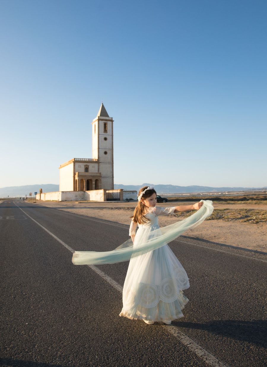 Niña de comunión girando el vestido en la carretera junto a la iglesia