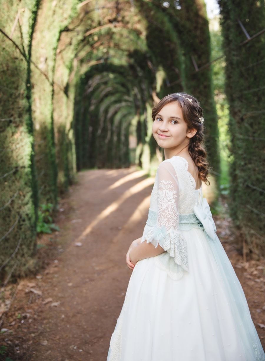 Niña de comunión en el sendero bajo los árboles