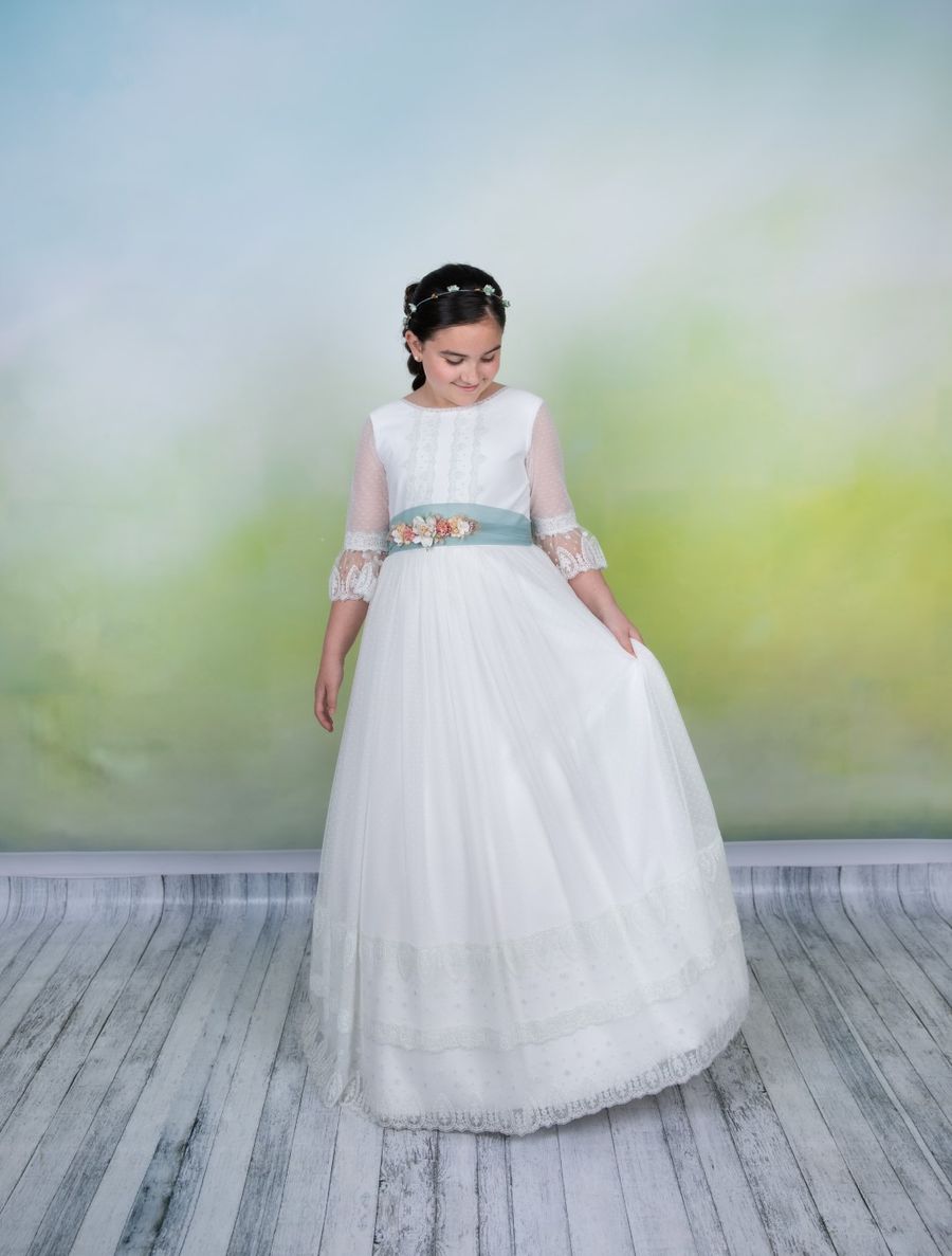Niña de comunión de pie con fondo pintado en el estudio