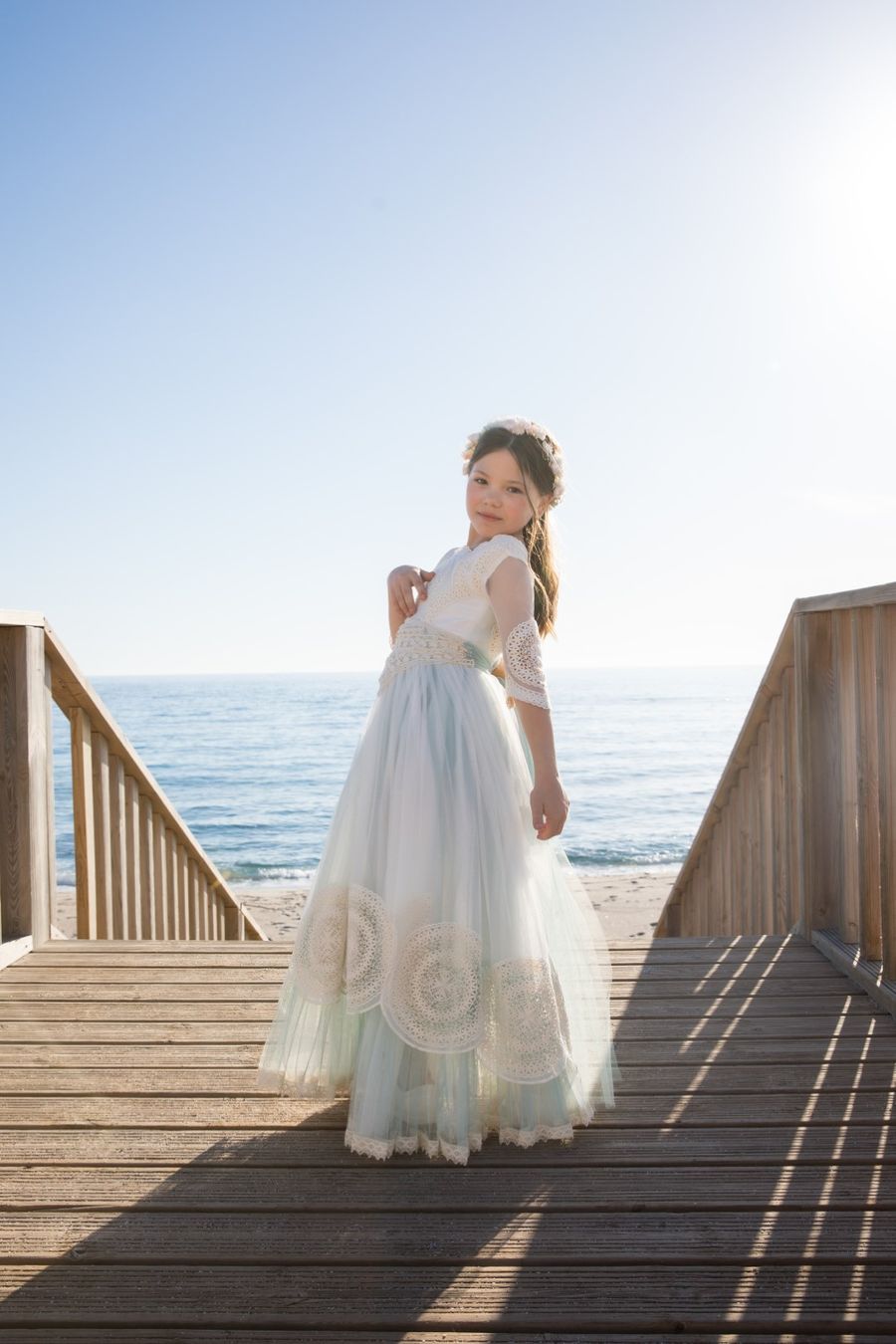 Niña de comunión en la pasarela de madera junto al mar