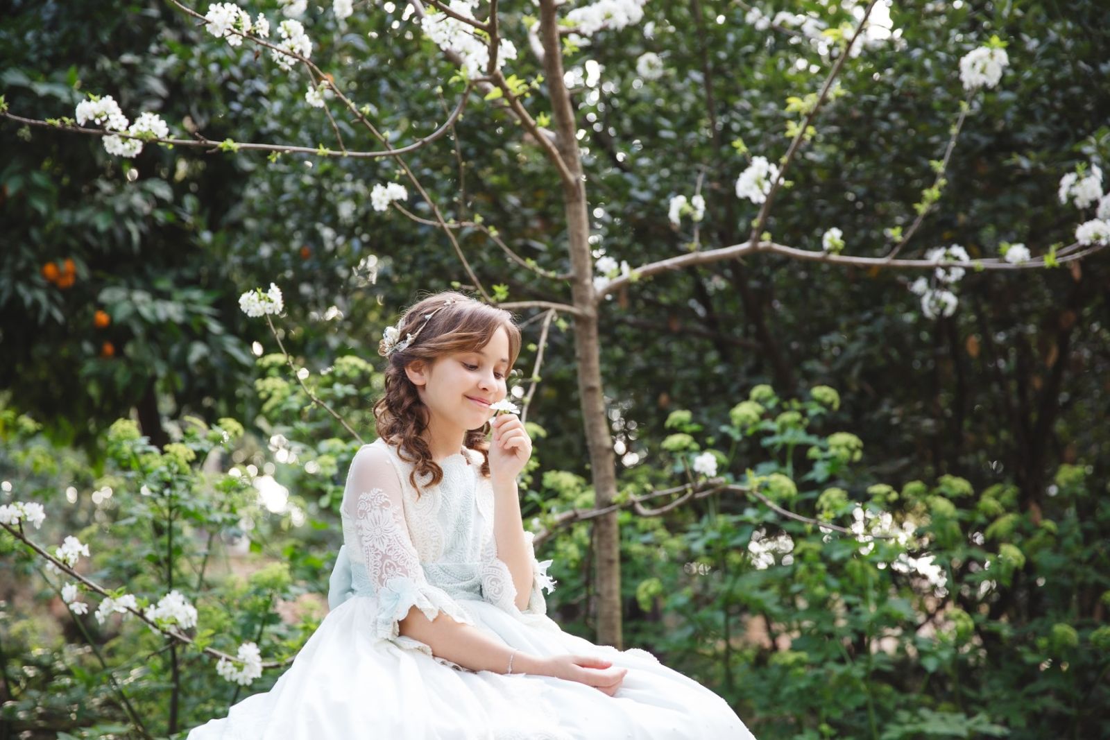 Niña de comunión entre flores blancas