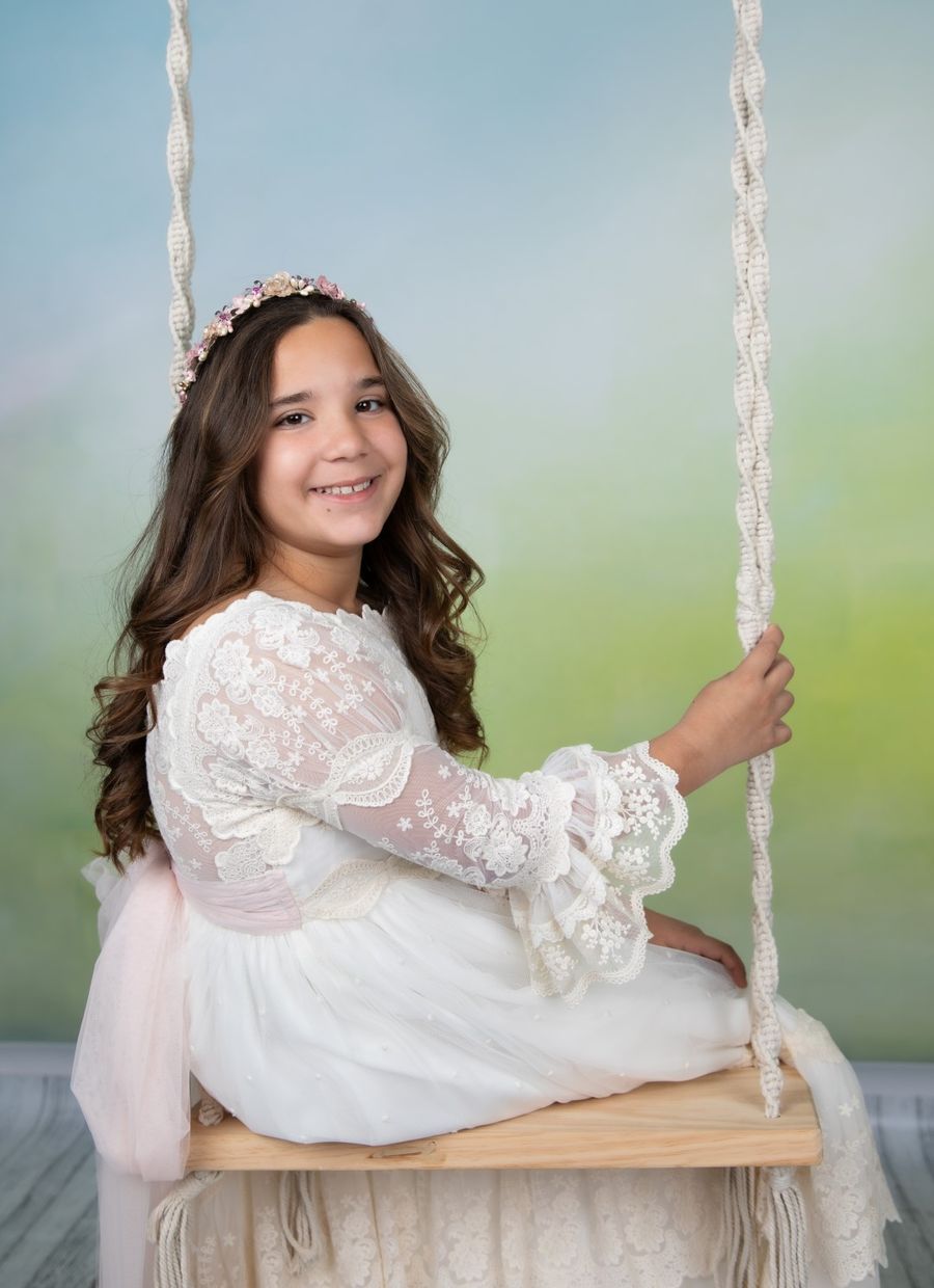 Niña de comunión en un columpio en el estudio