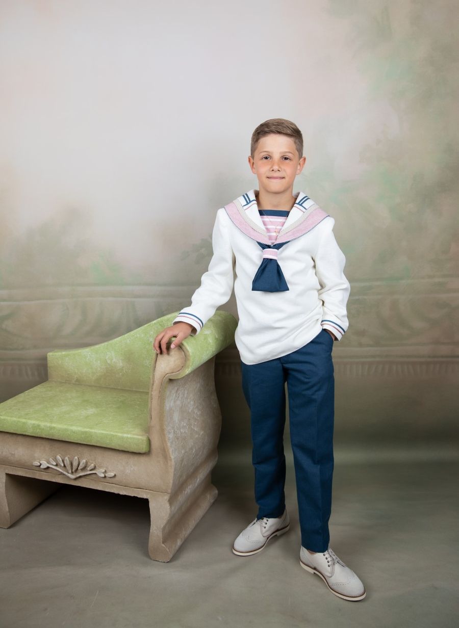 Niño de comunión de marinero junto a un sillón