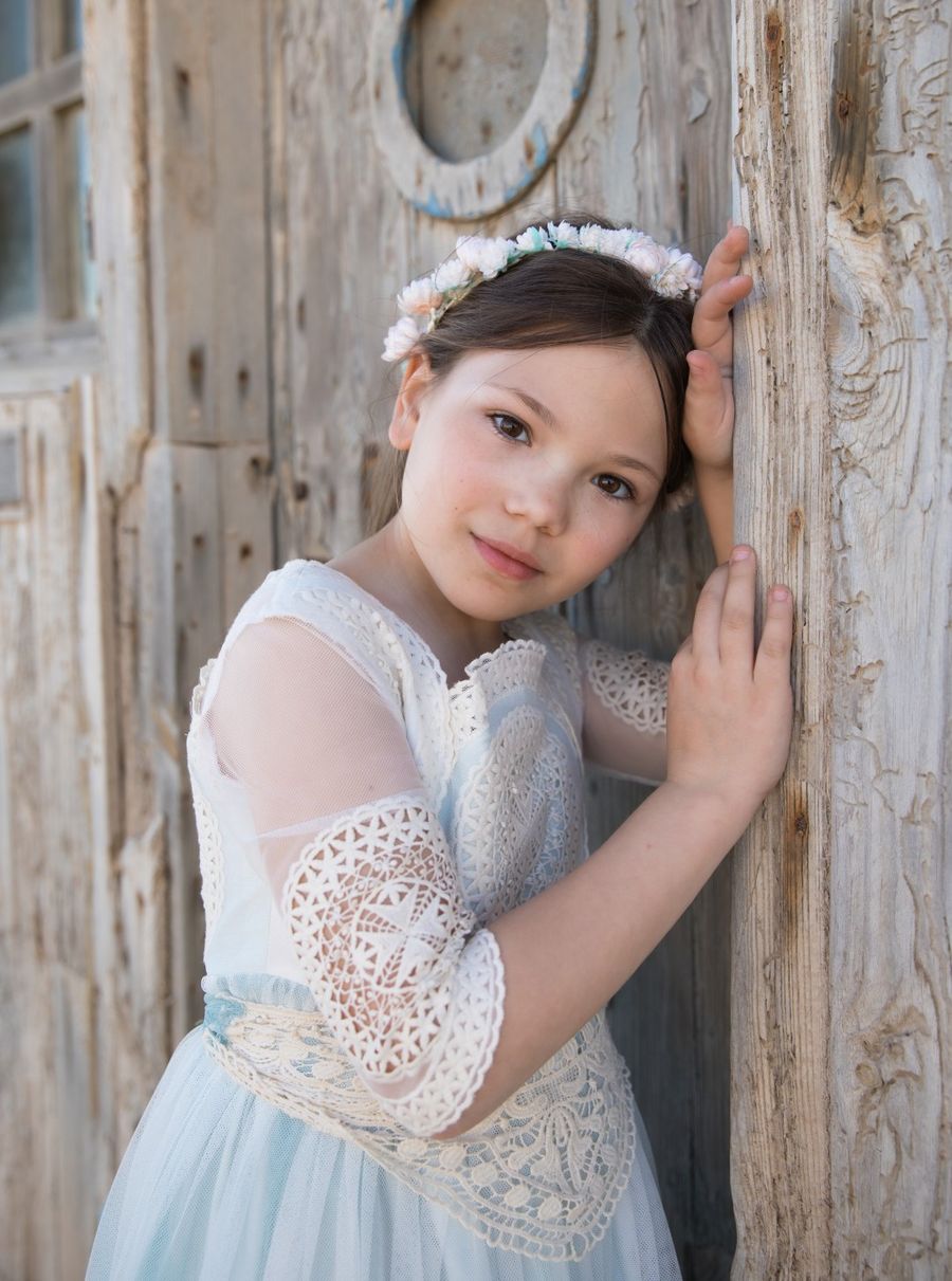 Niña de comunión apoyada en una puerta antigua de madera