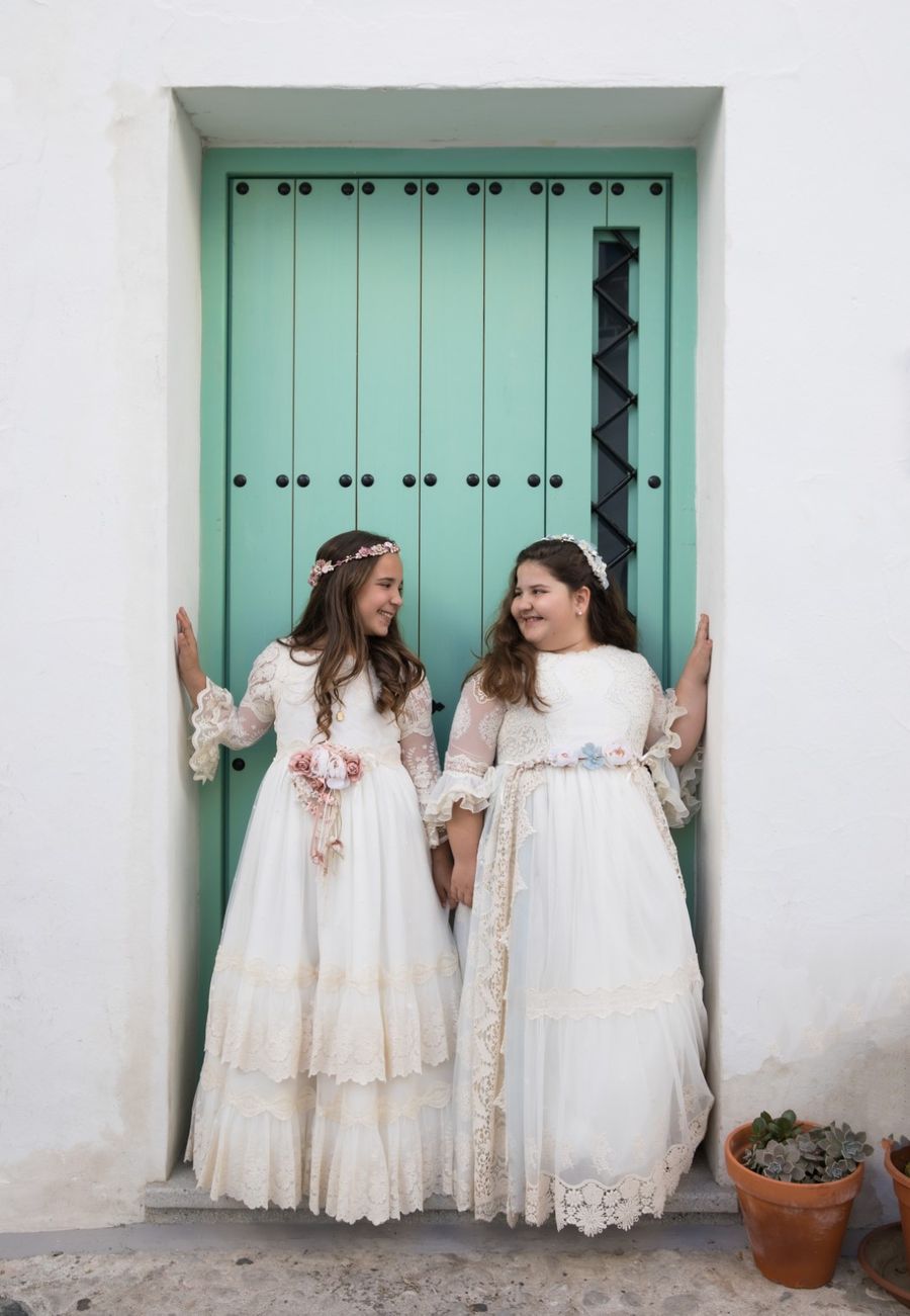 Dos niñas de comunión ante una puerta verde