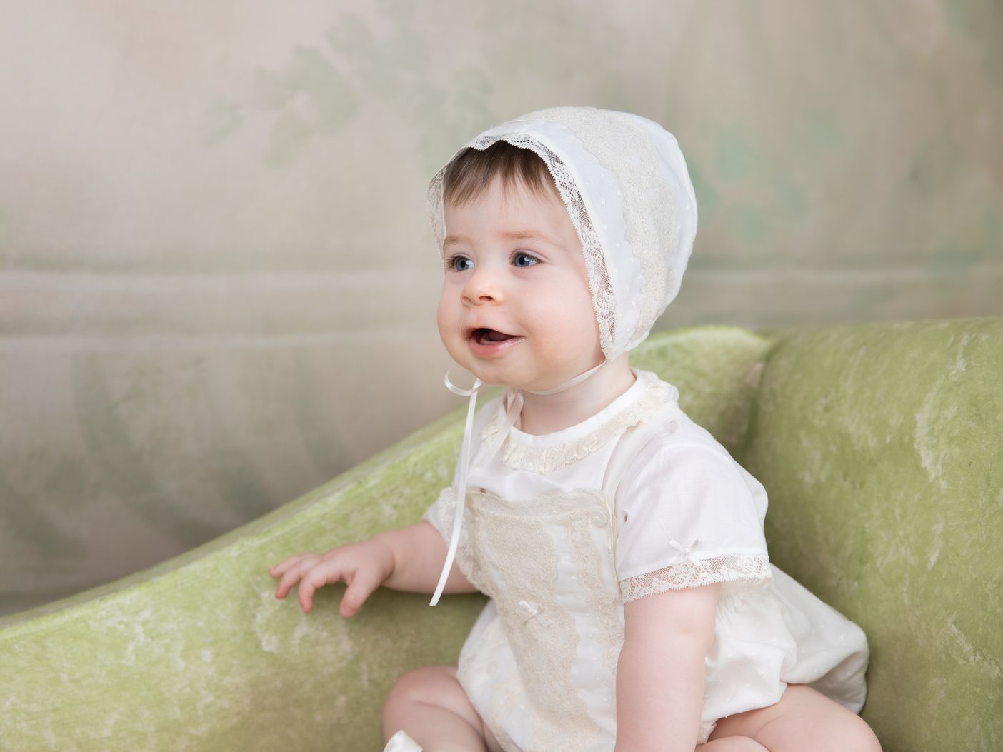 Bebé con gorrito en un sofá verde