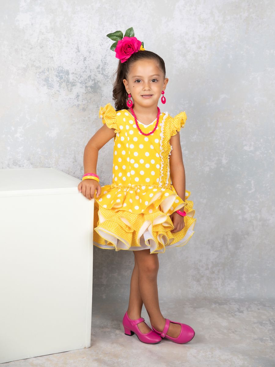 Niña de flamenca de pie junto a un cubo blanco