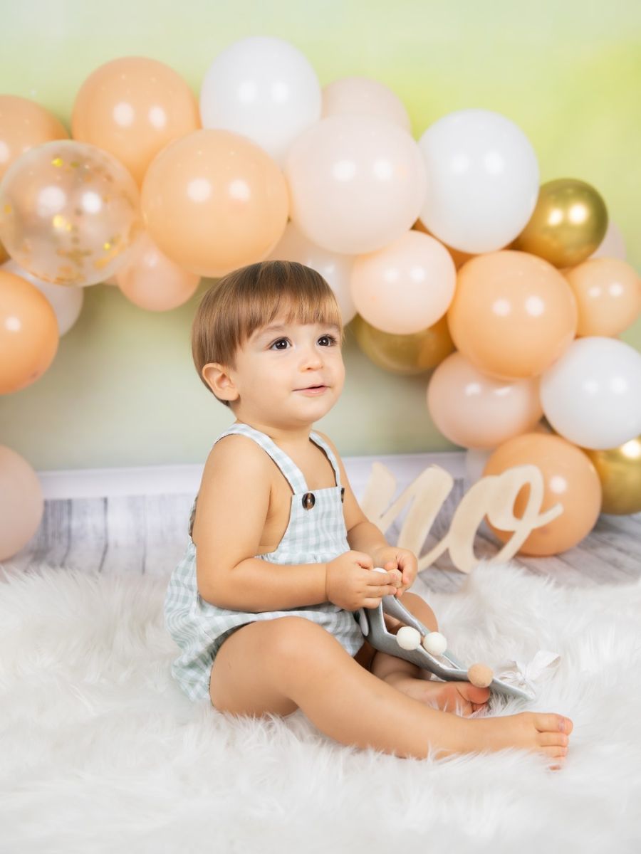 Bebé sentado ante un arco de globos en su primer cumpleaños