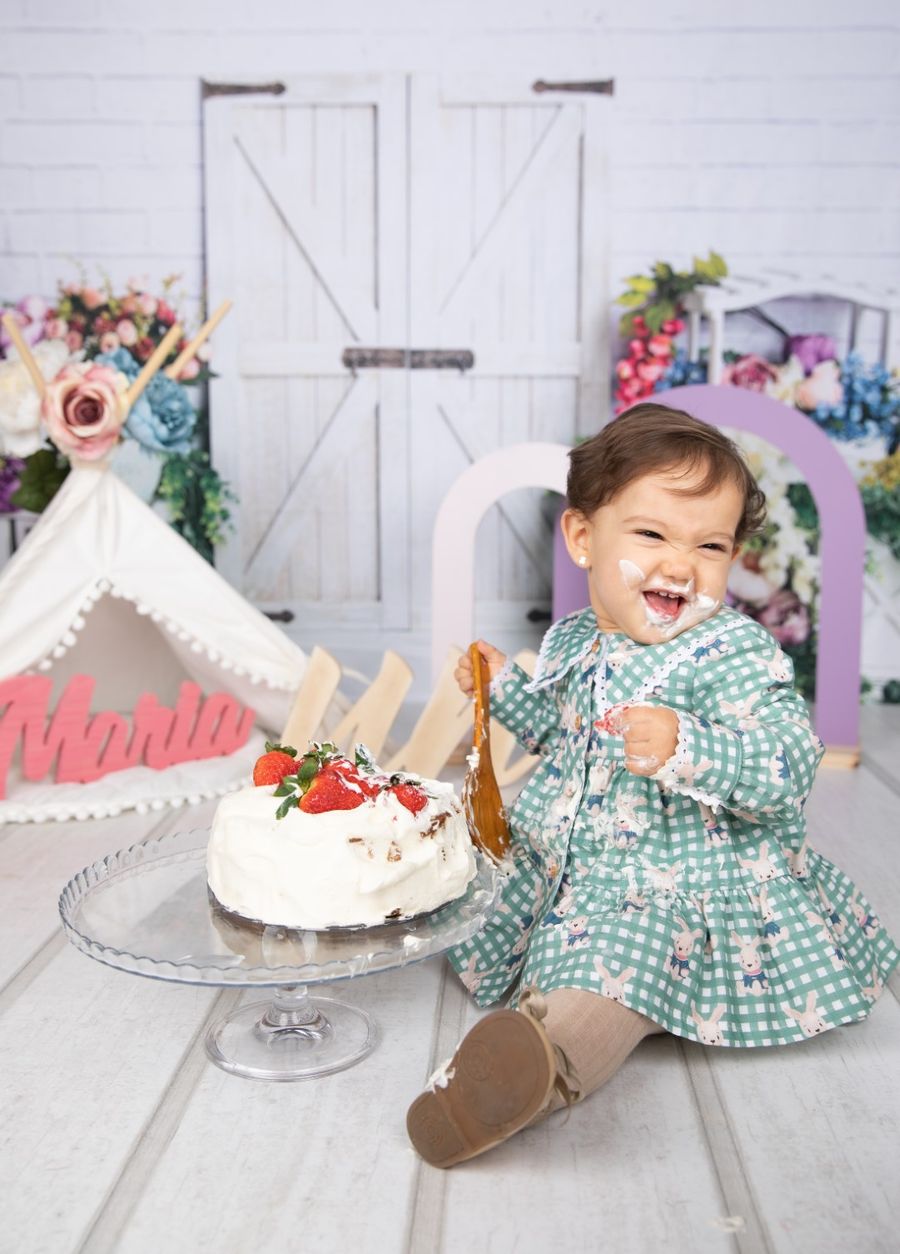 Bebé sentada junto a la tarta de cumpleaños